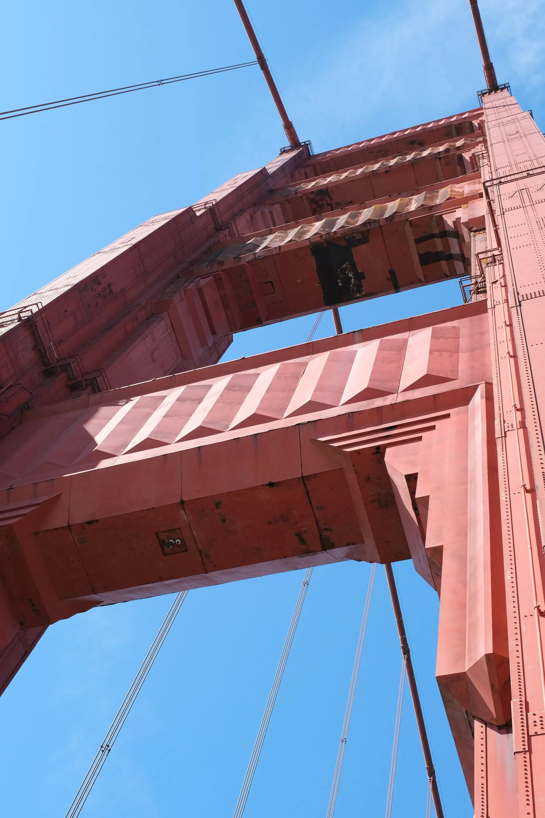 A close view looking up at the red structure of the Golden Gate Bridge