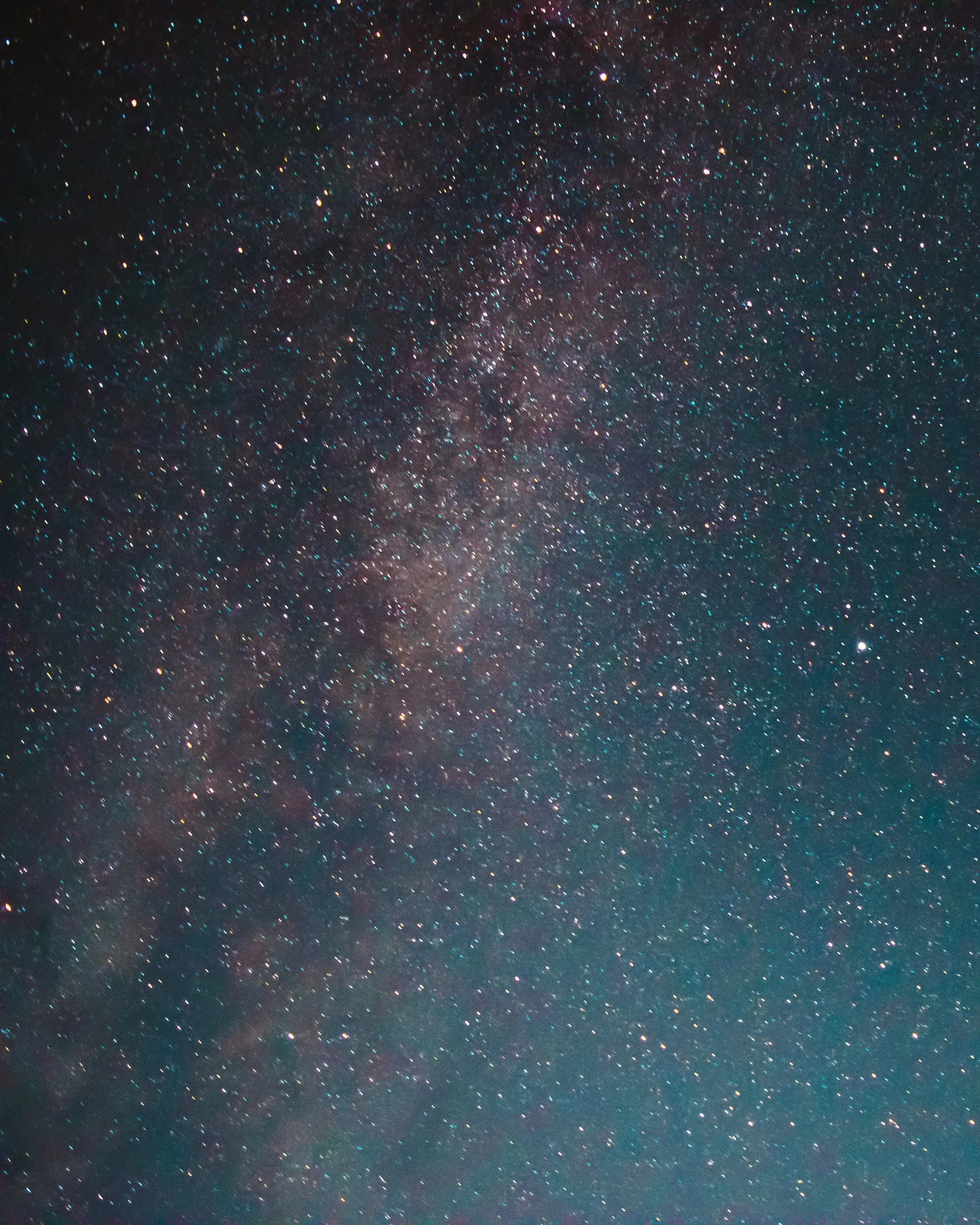 The Milky Way stretching vertically across a blue-green night sky