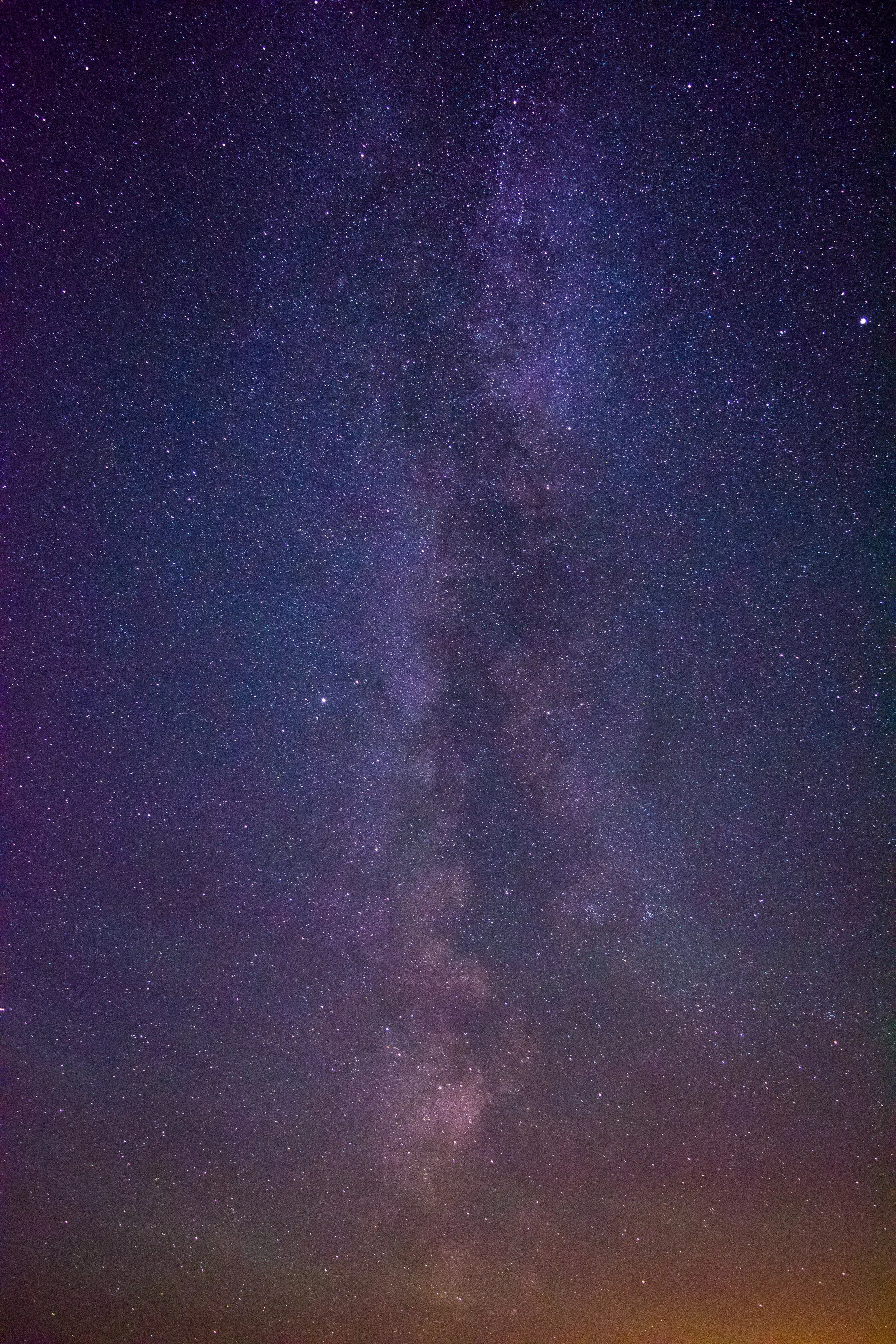The Milky Way glowing violet above a warm horizon